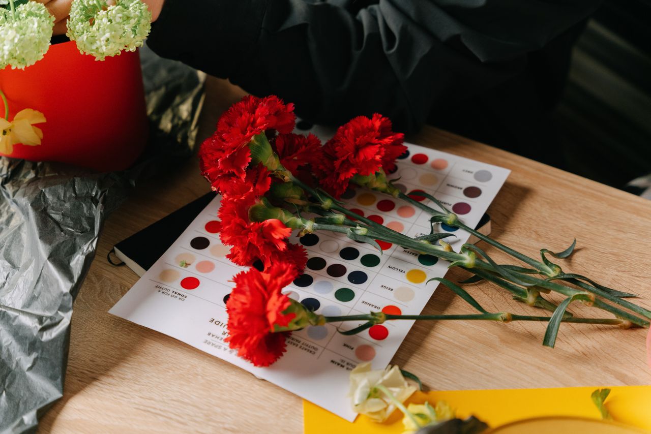 Carnation flowers atop a colorful workspace table, perfect for creative inspiration.