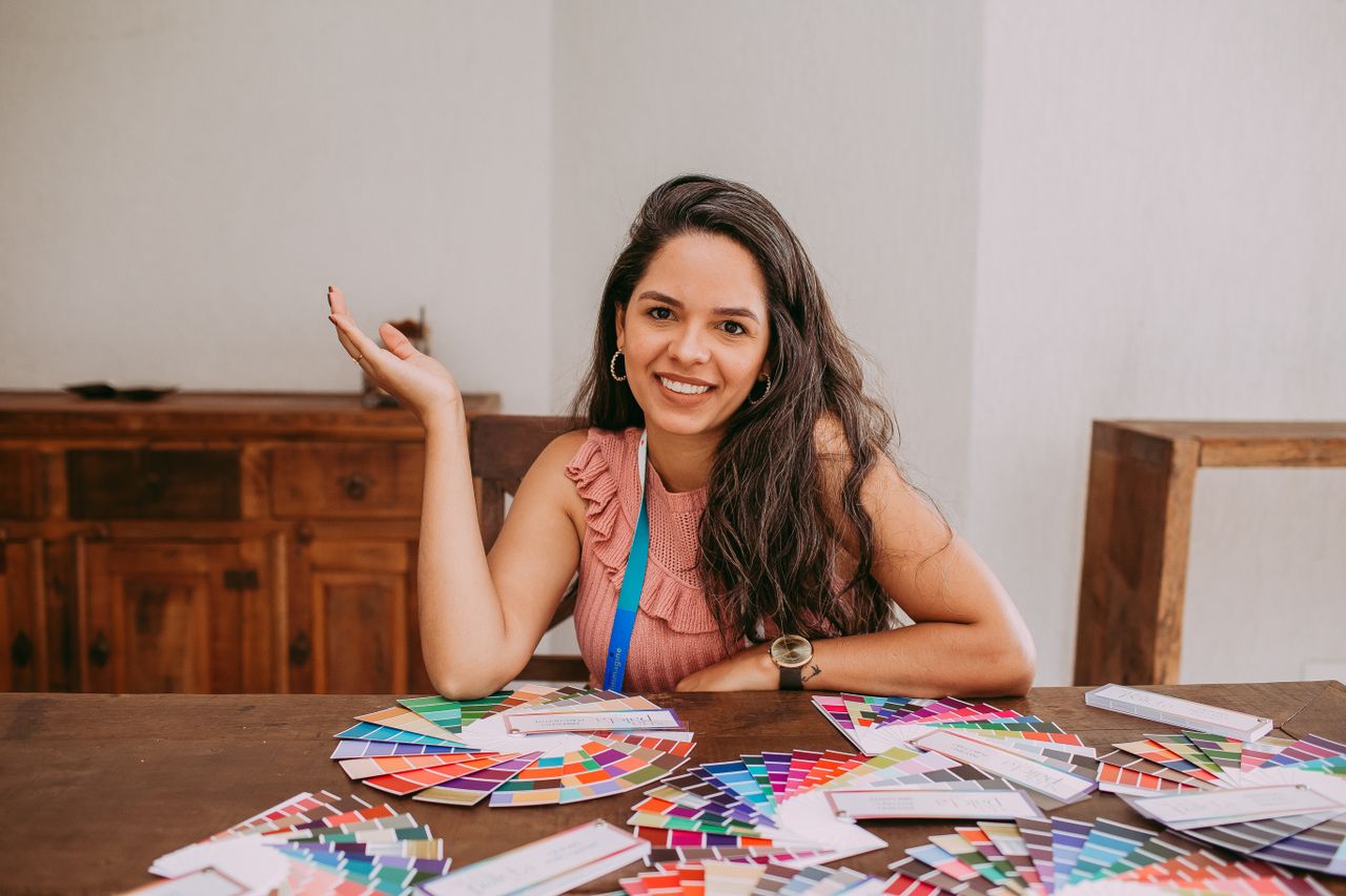 Young woman smiling with color samples on a wooden table. Perfect for design-related themes.