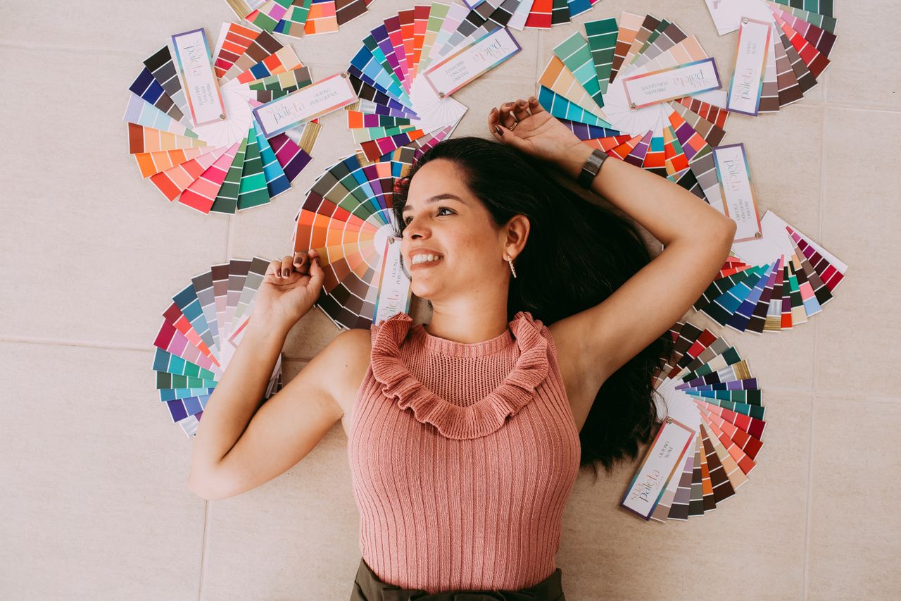 Happy woman lying surrounded by colorful palettes, showcasing vibrant design inspiration.
